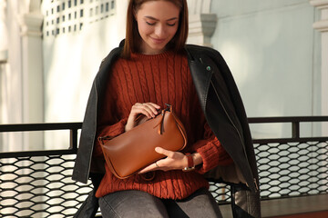 Fashionable young woman with stylish bag on city street