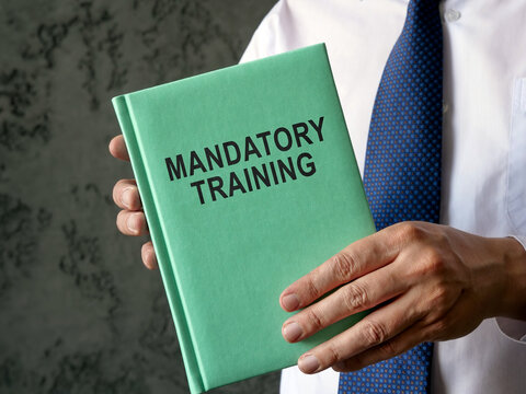 Employee holds mandatory training guide in the hands.
