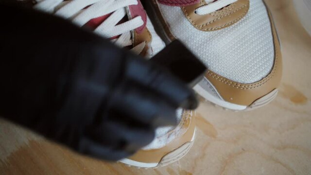 Worker cleaning sneakers with brush and professional cleaning stuff in shoes workshop. Sneaker Cleaning Service.