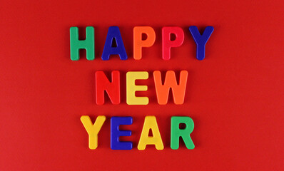 Inscription "Happy New Year" by multicolored plastic letters on a red background