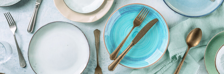 Tableware and cutlery panorama, shot from the top, with a vibrant blue plate. Catering panoramic...