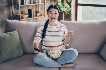 Full size photo of young excited mature woman eat popcorn humor joke watch cinema quarantine sit divan indoors