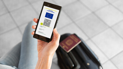  EU Digital Covid Certificate app for smartphone with quad code. Woman leaving with passport and baggage. Covid-19 concept.