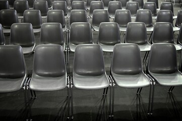 monochromatic image of gray empty audience seats arranged in rows selective focus