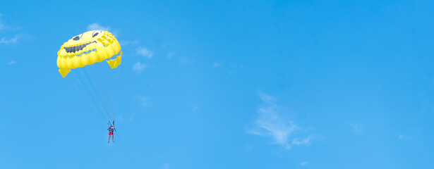 Yellow parachute with a man flying in the sky on a sunny day, copy space. Parasailing. Banner