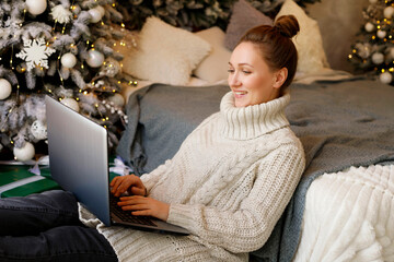 Young woman working or learning on her laptop sitting in living room in quarantine lockdown over...