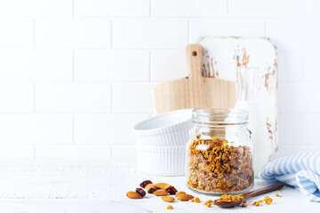 Oat granola with nuts and dried fruits to prepare a healthy breakfast on a bright kitchen table....