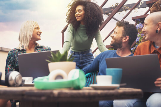  multiracial group of students use laptops on the university terrace.