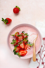 Breakfast with granola, coconut and strawberry smoothie in a bowl on a pink light background. Spring diet menu.Top view
