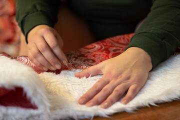 A woman sews a Santa Claus costume on a home sewing machine
