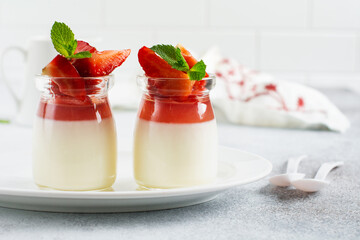 Festive dessert with berry jelly, vanilla panna cota and fresh strawberry on gray concrete table background. Selective focus