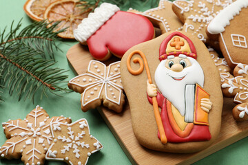 Tasty gingerbread cookies and fir branches on green background. St. Nicholas Day celebration - obrazy, fototapety, plakaty