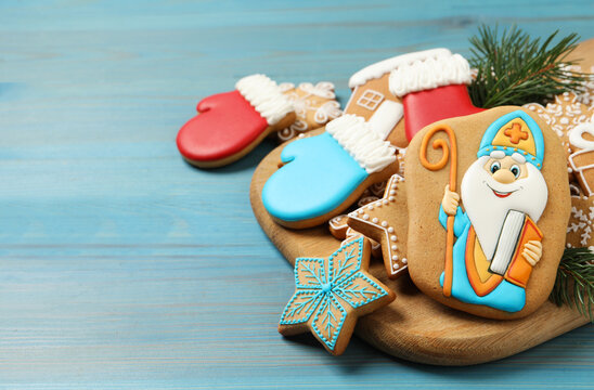 Tasty gingerbread cookies and fir branches on light blue wooden table, space for text. St. Nicholas Day celebration