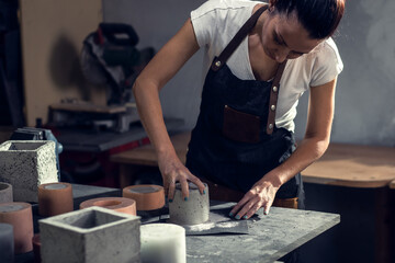 Craftswoman in apron working in her workshop making decorative concrete vase.	