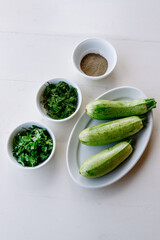 Baby zucchini on a white plate background. over white wooden table.  Organic food.