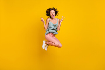 Fototapeta na wymiar Full length photo of excited happy woman jump up show v-signs smile cool isolated on yellow color background