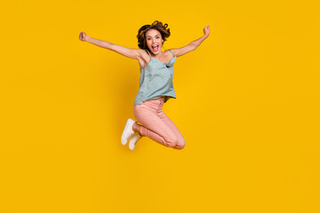 Full length photo of amazed excited happy woman jump up raise hands good mood isolated on yellow color background