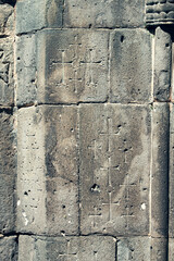 Wall of an ancient medieval Armenian church with carved crosses and other Christian attributes as a background