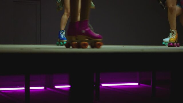4K Female legs in roller blades, skating fast at the roller park on floor . Close-up legs of young women is professionally skating . Different kind of and colorful vintage  roller blades . Slow Motion