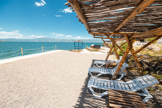 Sun loungers and sunbeds near the sandy beach on Lake Sevan in Armenia. Rest and vacation concept