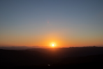 bright sun disappearing behind the mountain in the late afternoon at sunset