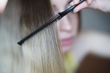 Lock of hair shatush close-up. The process of combing with a thin black comb