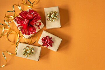 Many gift boxes with a bright shiny red bow, on a bright orange (yellow) background. Present for birthday, christmas, new year. Festive concept.