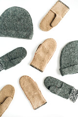 Grey and beige craft warm winter mittens and bonnets on white background. Aesthetic minimalist DIY concept. Flat lay, top view fashion pattern