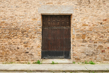 Stone wall with old entrance and wooden door