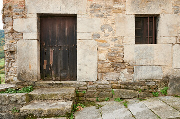 Fototapeta na wymiar Stone wall with old entrance and wooden door