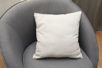 White square canvas pillow mockup on grey armchair, small cotton cushion mockup in living room...