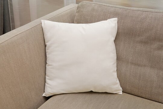 White square canvas pillow mockup on cozy couch,  small cotton cushion mockup in living room interior., space for design presentation.