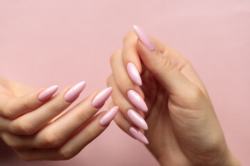 Girl's hands with a beautiful pink manicure on a light pink background
