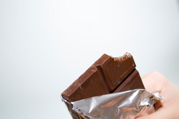 Children's hands hold a bar of chocolate on a white background.