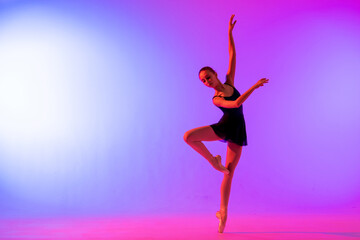 Fototapeta na wymiar Beautiful young girl ballerina in pointe shoes and pink leotard silhouette on bright blue background.