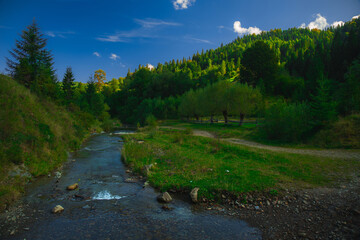 morning highland meadow picturesque scenic view place with mountains around with river stream in spring time season, shadow from ridge