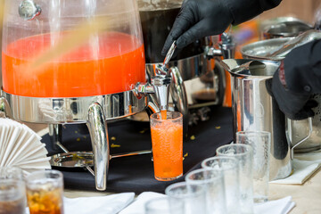 A glass is filling juice from juice tank. glass for water refill from water tank at the coffee shop...