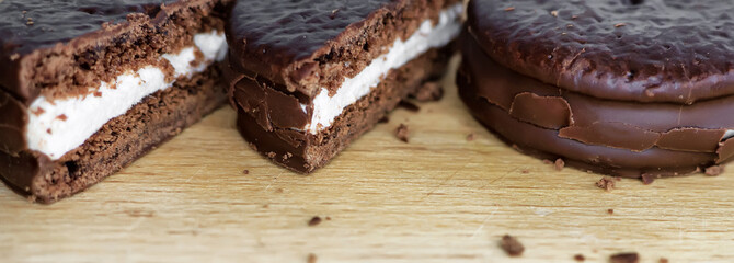 Cookies in chocolate glaze and cream filling on a wooden background.