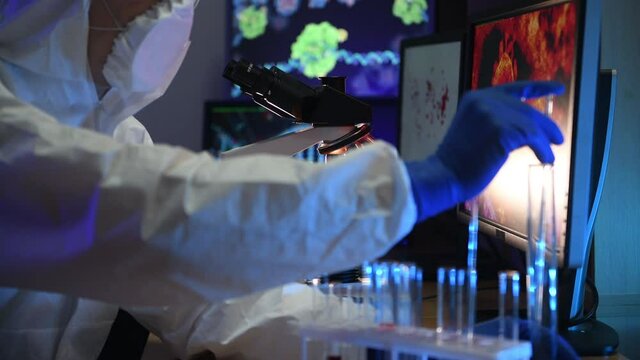 A man in biological defense works in a viral laboratory. He looks at the samples under an microscope, conducts experiments looking for a vaccine for the disease.