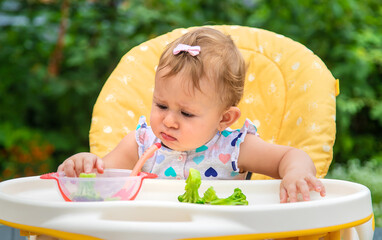 Baby eats pieces of broccoli vegetables. Selective focus.