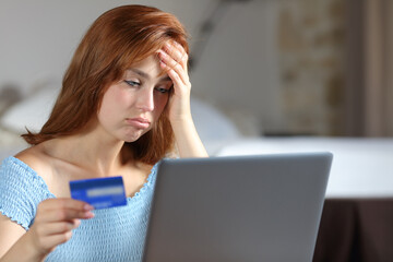 Frustrated woman paying online in the bedroom