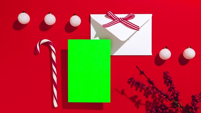 Greeting card, invitation, blank paper mockup with copy space and Xmas decorations, top view on a christmas background. Stop motion animation.