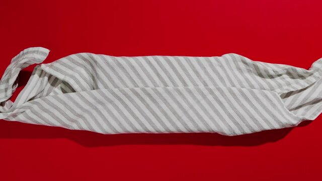 Zero waste gift wrapping traditional Japanese furoshiki style on a red background. Plastic free, hand made gift package for Christmas and other festive occasions. Stop motion animation.