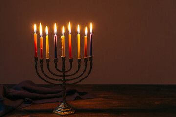Jewish Holiday Hanukkah background with candles and traditional candelabra menorah on dark background. Jew festival of lights concept.
