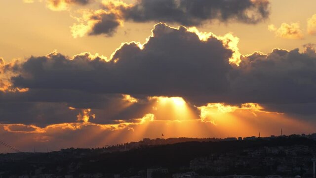 Sun beams shine through dark clouds moving fast, time lapse of Asian side of Istanbul in summer morning. Bright sunlight flash through opening in clouds at end of clip