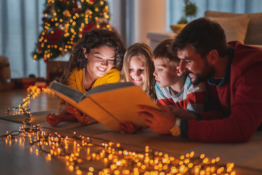 Parents and children reading fairytales while spending Christmas Eve together at home