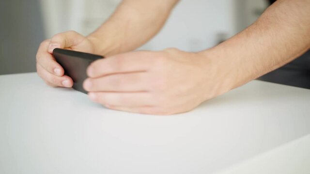 Close-up, a man uses a smartphone with a green screen while standing at the table. The camera rotates around 360 degrees 