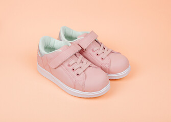 Cute pink children's sneakers. Orange background. Baby clothes and shoes