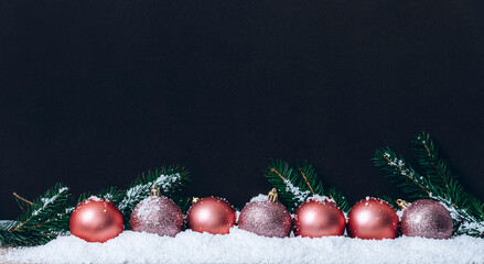 Pink christmas balls with snowflakes on dark brown wall. Elegant Christmas decoration background....