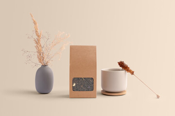 Blank tea packaging with a transparent window, teacup, dried plants, sugar stick, front view, on a warm background, packaging mockup with empty space to display your branding design.
